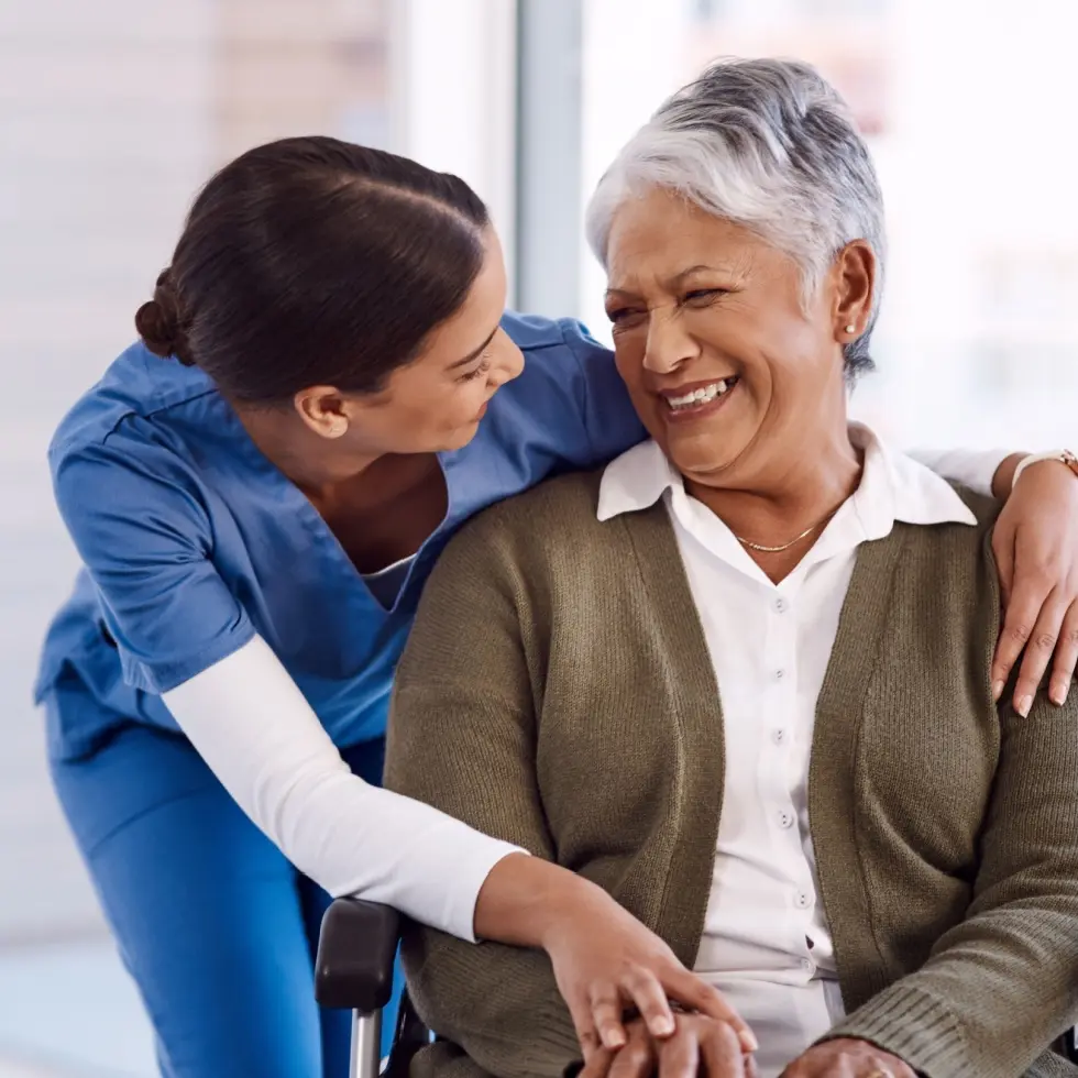 nurse hugging an old woman in a wheelchair