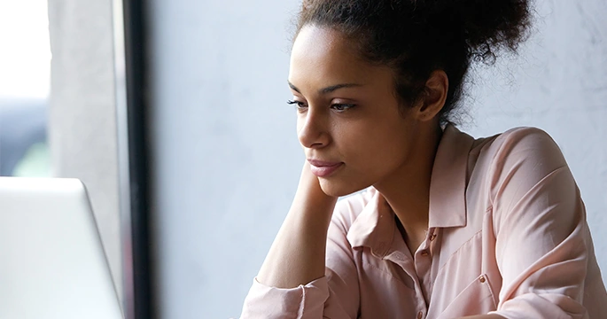 Young woman with dry eyes from too much screen time looking at her computer