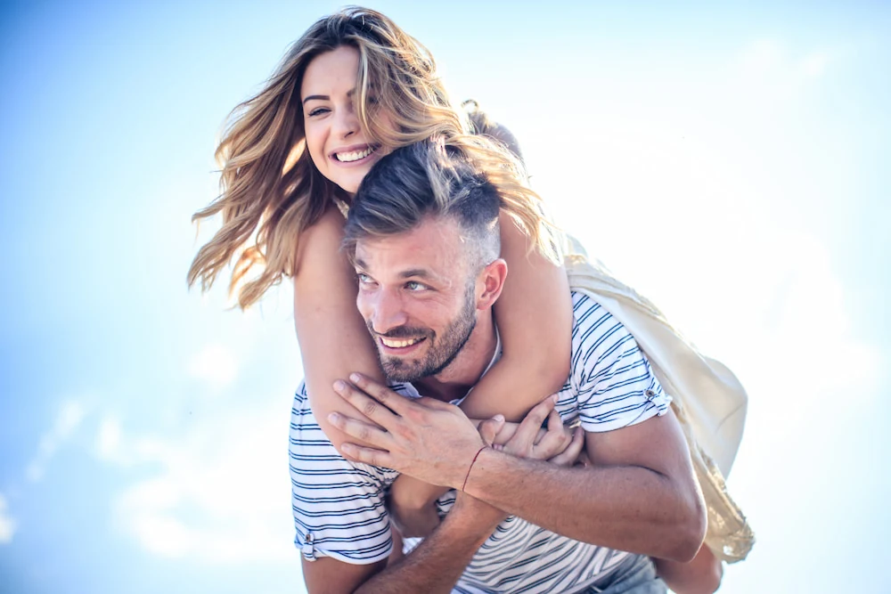 Happy couple piggyback ride outside