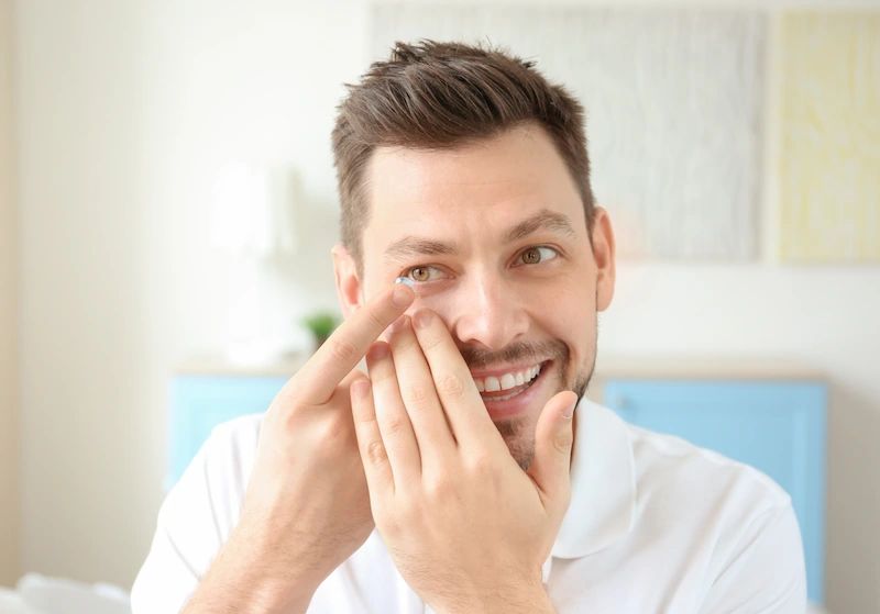 man smiling while putting in contact lens