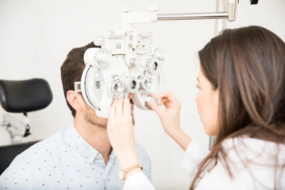 young man having eyes examined by ophthalmologist or optometrist